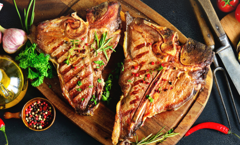 Grilled T-bone steaks with fresh herbs, vegetables and wine bottle