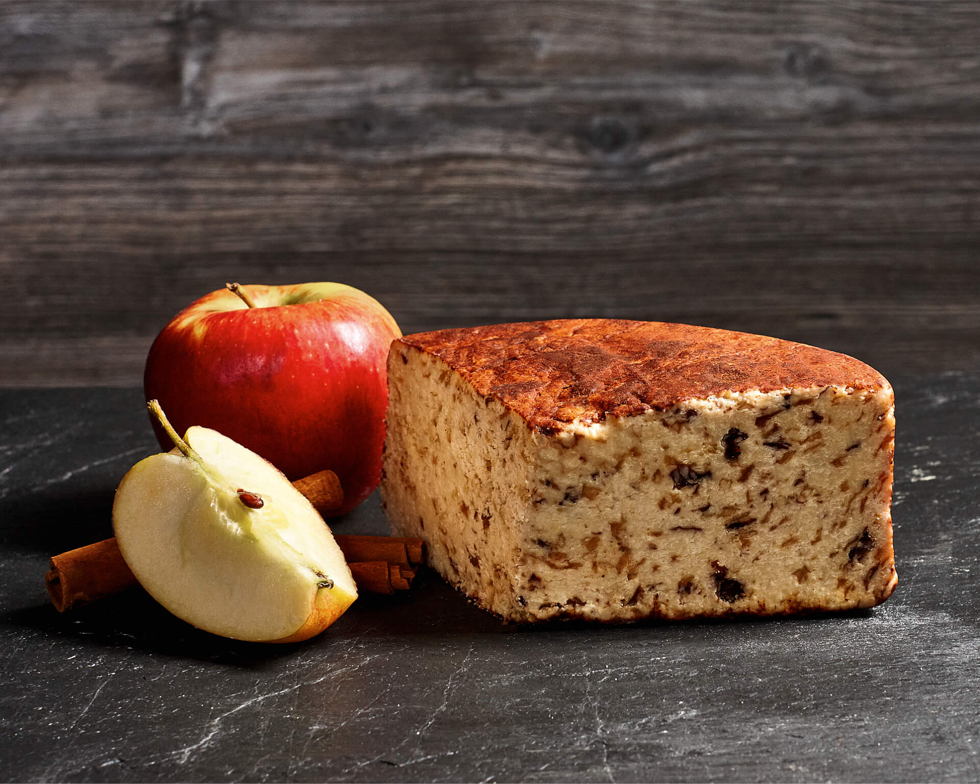 Ein köstliches Stück Käse und ein Apfel vor dunklem Hintergrund
